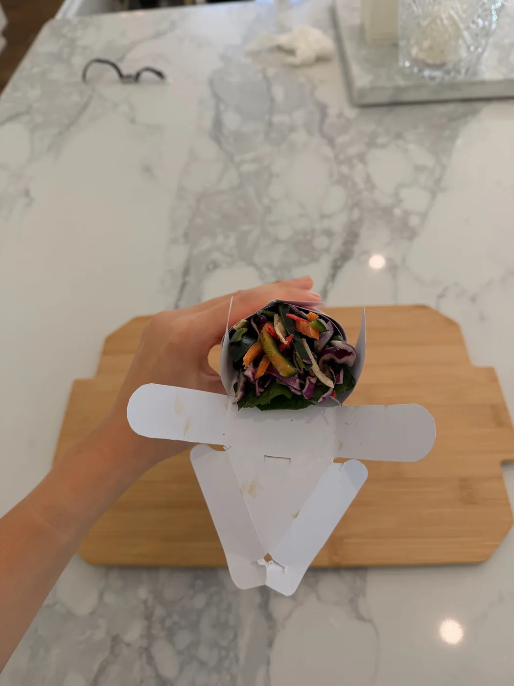 A hand holding the tray folded around shredded vegetables